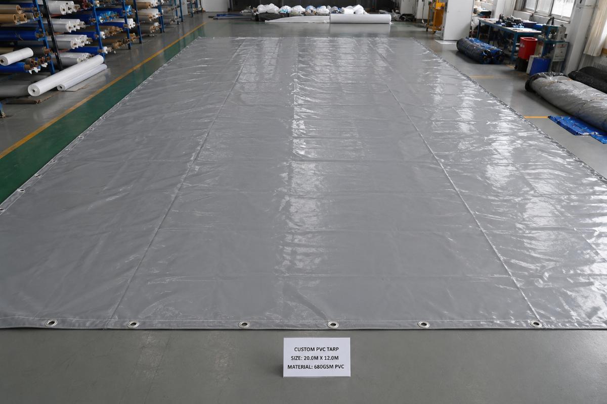 A large single-piece custom PVC tarp laid out for inspection before shipment