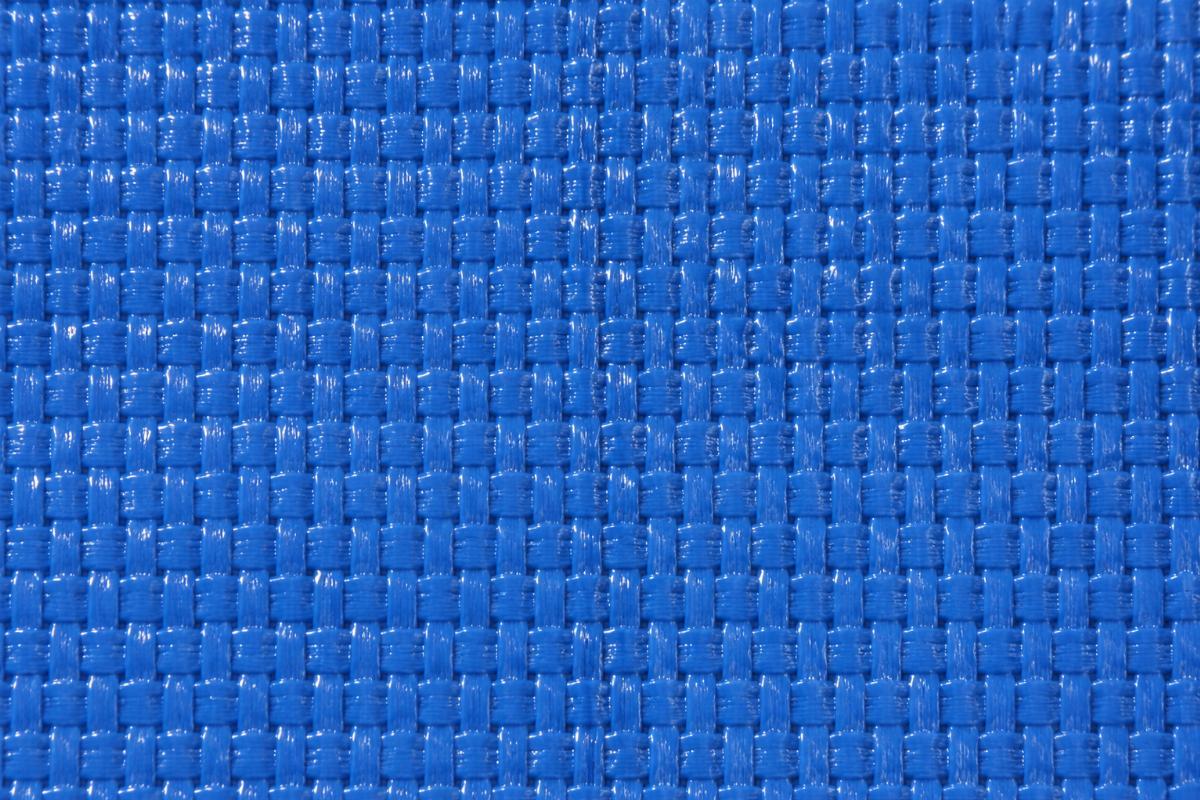 Close up of woven PVC mesh tarpaulin material showing uniform coating and weave pattern