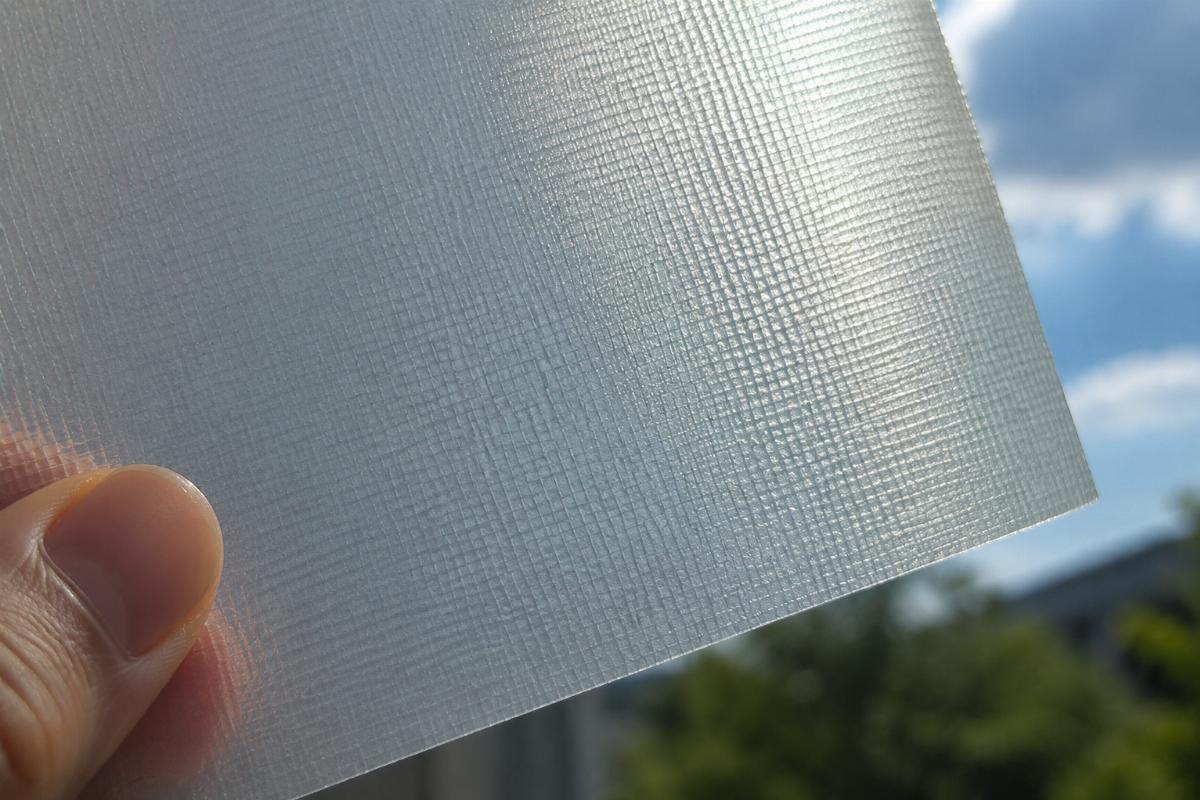Close up view of knife-coated PVC fabric material held up against natural light